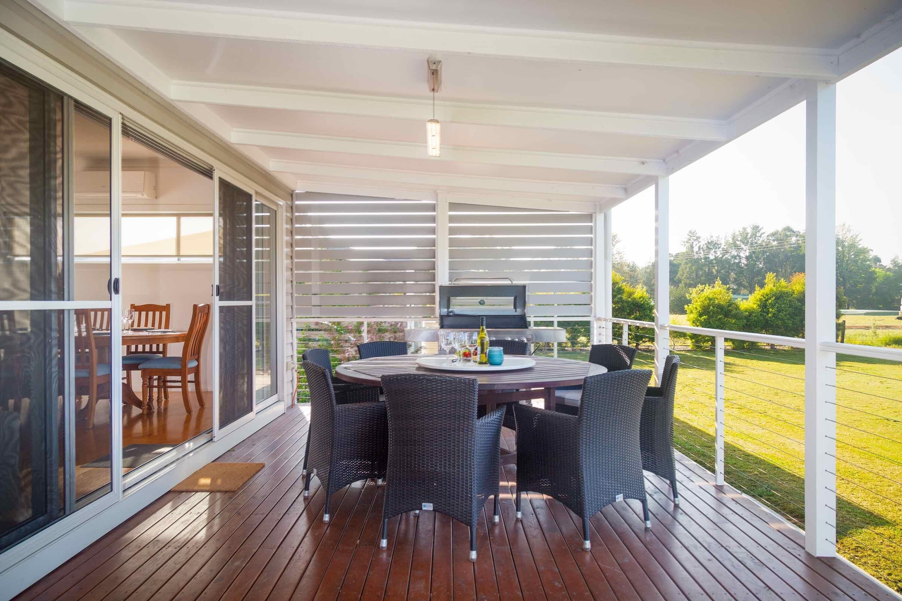 An outdoor patio with a round table, chairs, and a grill.