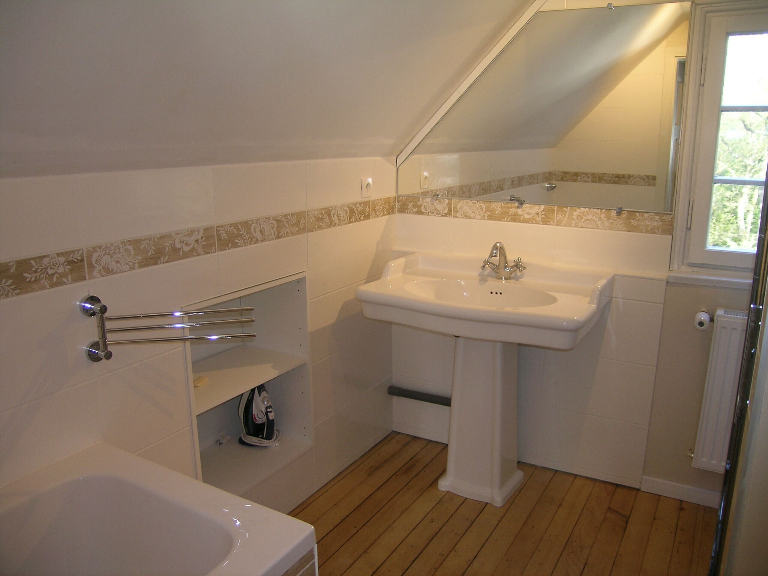 A bathroom with a white sink, a mirror, and a shower.