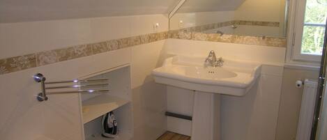 A bathroom with a white sink, a mirror, and a shower.