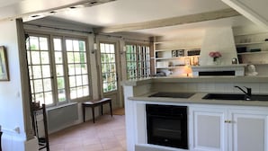 Una cocina con armarios blancos, estufa negra y ventana con vista a follaje.