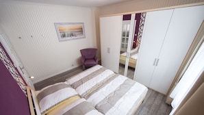 Une chambre à coucher avec un lit, une chaise, une armoire et un tableau accroché au mur.
