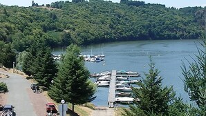 A lakeside road with parked cars and a dock with boats.