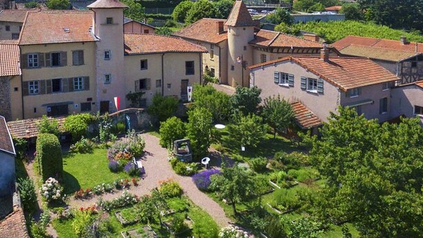 A courtyard with a garden, a tower, and buildings with red-tiled roofs.
