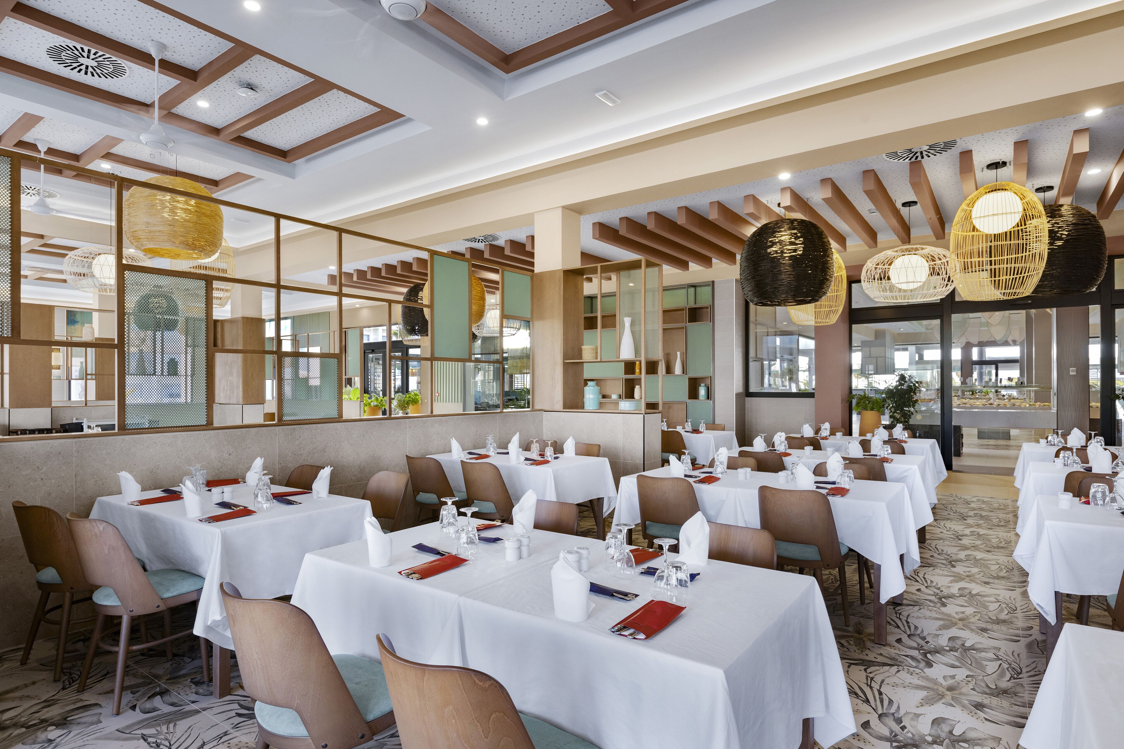 Un restaurante con varias mesas dispuestas para comer, con manteles blancos y sillas.