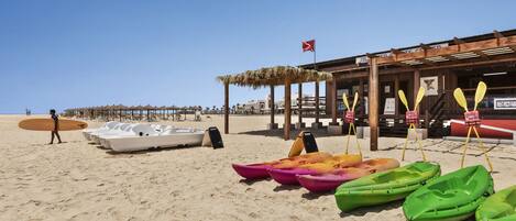 A beach with kayaks and a paddleboarder.