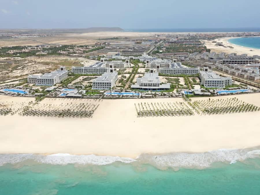 Na praia, espreguiçadeiras, guarda-sóis, prática de windsurfe