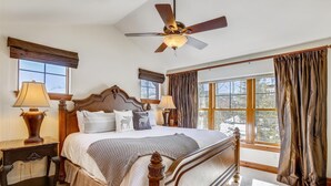 A well-lit bedroom with a large bed, two bedside tables, a ceiling fan, and a view of the outdoors through a window. - Breck Townhome, Hot Tub, Great Views, Seasonal Shuttle, Sleeps 10 (Breckenridge)
