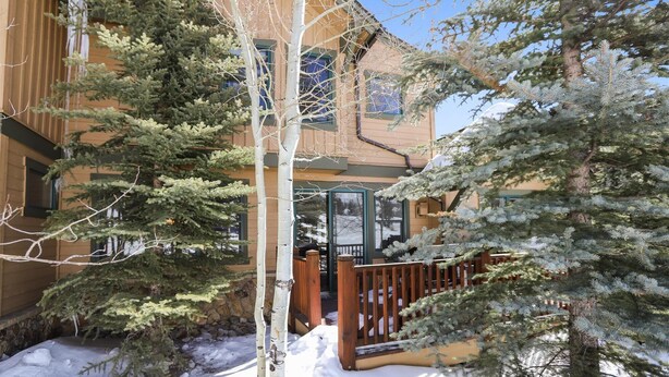 A two-story building with a wooden exterior, a stone foundation, and a wooden deck. - Breck Townhome, Hot Tub, Great Views, Seasonal Shuttle, Sleeps 10 (Breckenridge)
