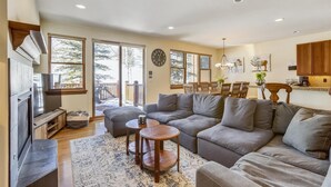 A spacious living room with a gray sectional sofa, a wooden coffee table, and a fireplace. - Breck Townhome, Hot Tub, Great Views, Seasonal Shuttle, Sleeps 10 (Breckenridge)