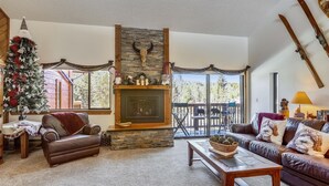 Una sala de estar acogedora con chimenea, muebles de cuero y un árbol de Navidad.