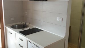 A modern kitchen with white cabinetry, a stainless steel sink, and a black range hood. - Apartment 1624/16706 (Istria - Novigrad), 600m from the beach (Novigrad)