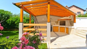 A modern outdoor kitchen area with a pergola structure, a built-in sink, and a stone countertop. - Apartment 1624/16706 (Istria - Novigrad), 600m from the beach (Novigrad)
