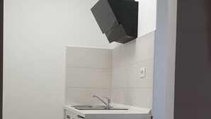 Uma cozinha compacta com pia embutida, fogão e coifa preta.