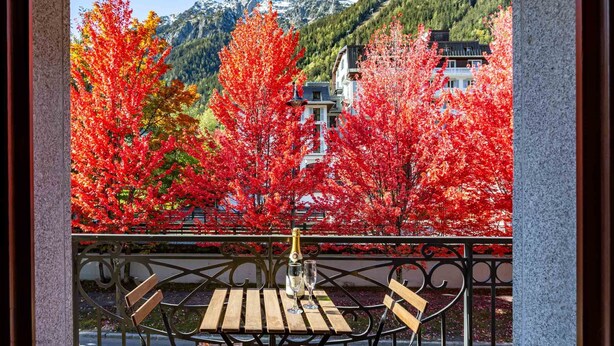 A terrace with a table and chairs, overlooking a mountain and autumn foliage. - Le Paradis 25 Apartment -  an apartment that sleeps 6 guests in 3 bedrooms (Chamonix-Mont-Blanc)