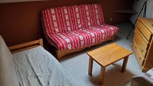 Ein kleiner, gemütlicher Raum mit einem rot-weiß gestreiften Sofa, einem Holztisch und einer Marmorbank.