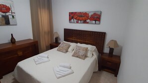 Une chambre d’hôtel avec un lit bien fait, une tête de lit en bois, une table de chevet avec une lampe et un tableau au-dessus du lit.