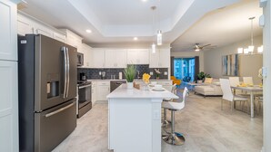 A modern kitchen with stainless steel appliances, a central island, and a dining area with a view.