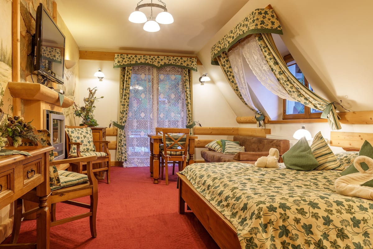 Une chambre confortable avec un lit en bois, un bureau, une chaise et une fenêtre avec des rideaux.
