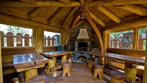 A rustic wooden interior with a stone fireplace, wooden benches, and a high ceiling. - Lesny Dworek (Zakopane)