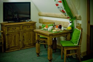 A dining area with a wooden table, chairs, a television, and a bench.