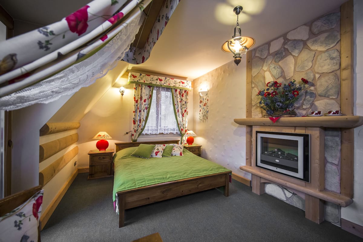 Une chambre confortable avec un lit en bois, une cheminée en pierre et un téléviseur.
