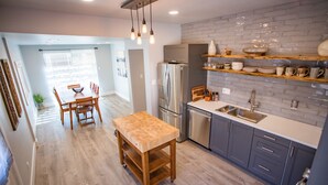 Una cocina moderna con una mesa de madera, electrodomésticos de acero inoxidable y un salpicadero de ladrillo.