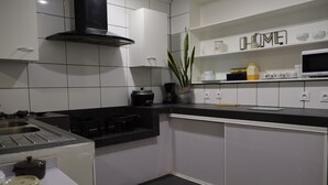Una cocina moderna con armarios blancos, encimera negra, estufa y microondas.