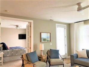 Amplia sala de estar con un sofá, dos sillones, una mesa de centro y un televisor en la pared.