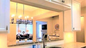 A modern kitchen with a double sink, granite countertops, and white cabinetry.