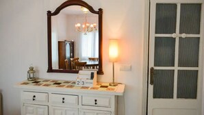 Une salle de bain avec un meuble-lavabo blanc, un miroir, un lustre et une porte avec une fenêtre.