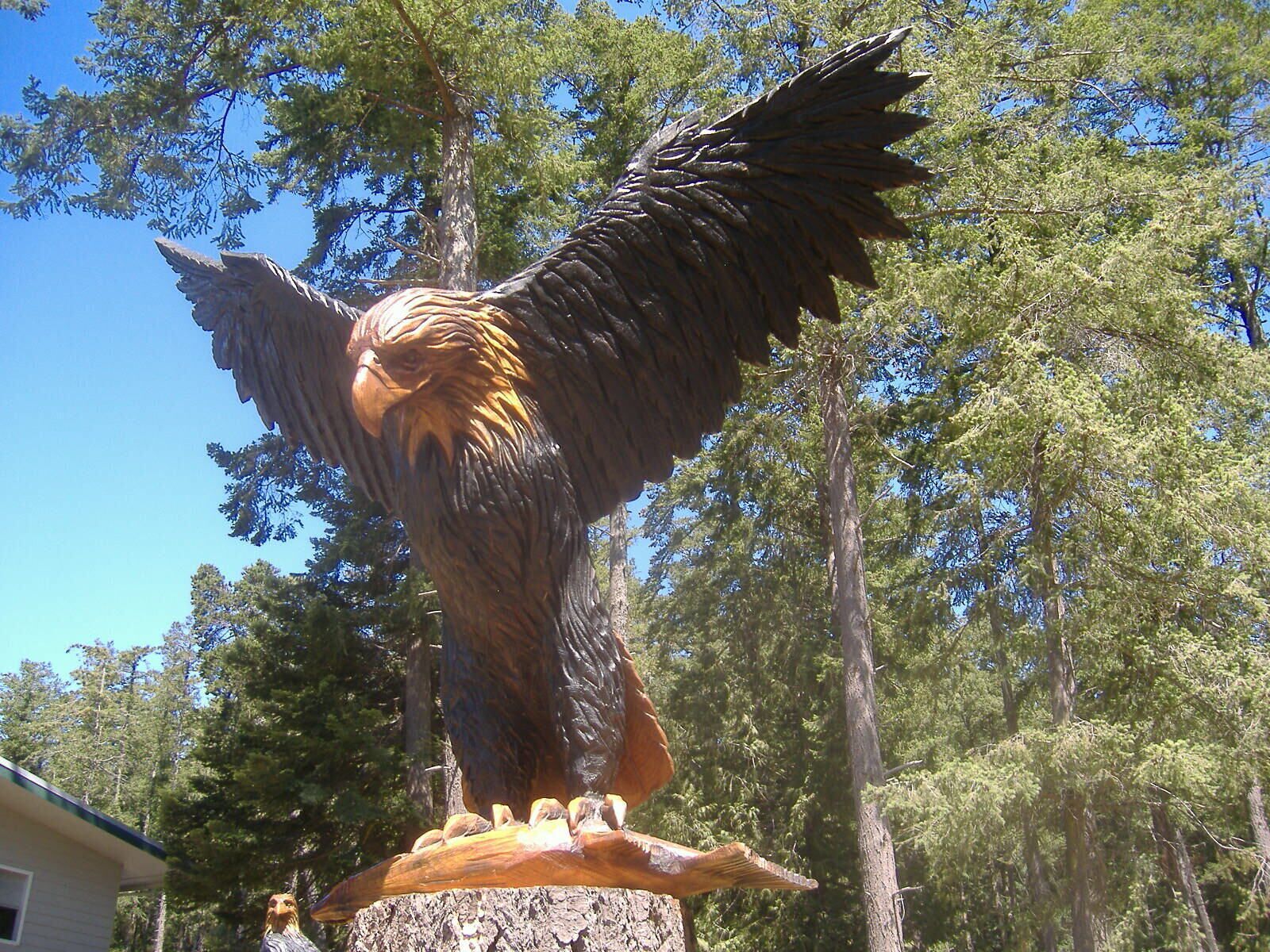 Una estatua de madera de un águila con alas extendidas, sobre un tocón de árbol.