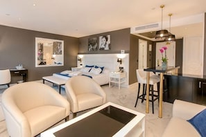 A modern hotel room with a bed, two armchairs, a coffee table, a dining area, and a kitchen. - Four Points by Sheraton Costa Blanca Resort (Benidorm)