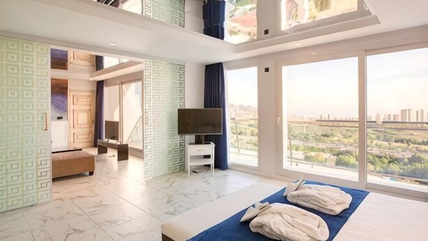 A hotel room with a bed, a TV, a balcony with a city view, and a large window. - Four Points by Sheraton Costa Blanca Resort (Benidorm)