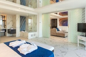 A modern hotel room with a large bed, a sitting area, a TV, and a bathroom. - Four Points by Sheraton Costa Blanca Resort (Benidorm)