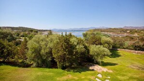 A coastal landscape with a grassy area, trees, and a view of the sea and distant mountains. - Hotel Club Baja Bianca (San Teodoro)