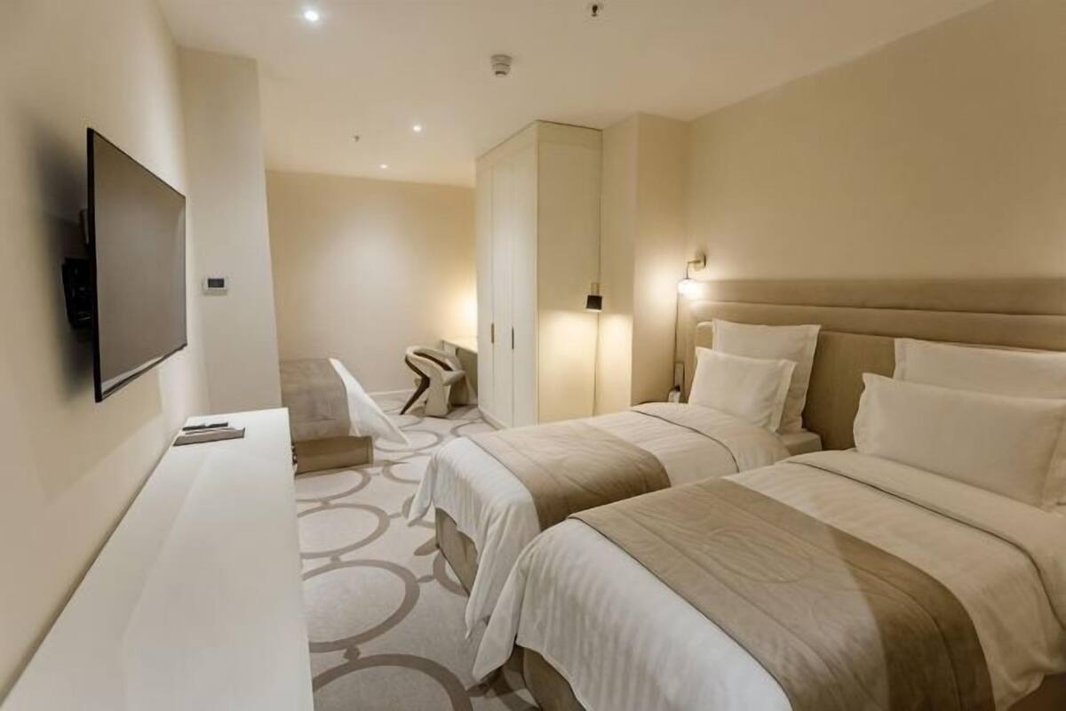 A hotel room with two beds, a TV, a desk, and a wardrobe.
