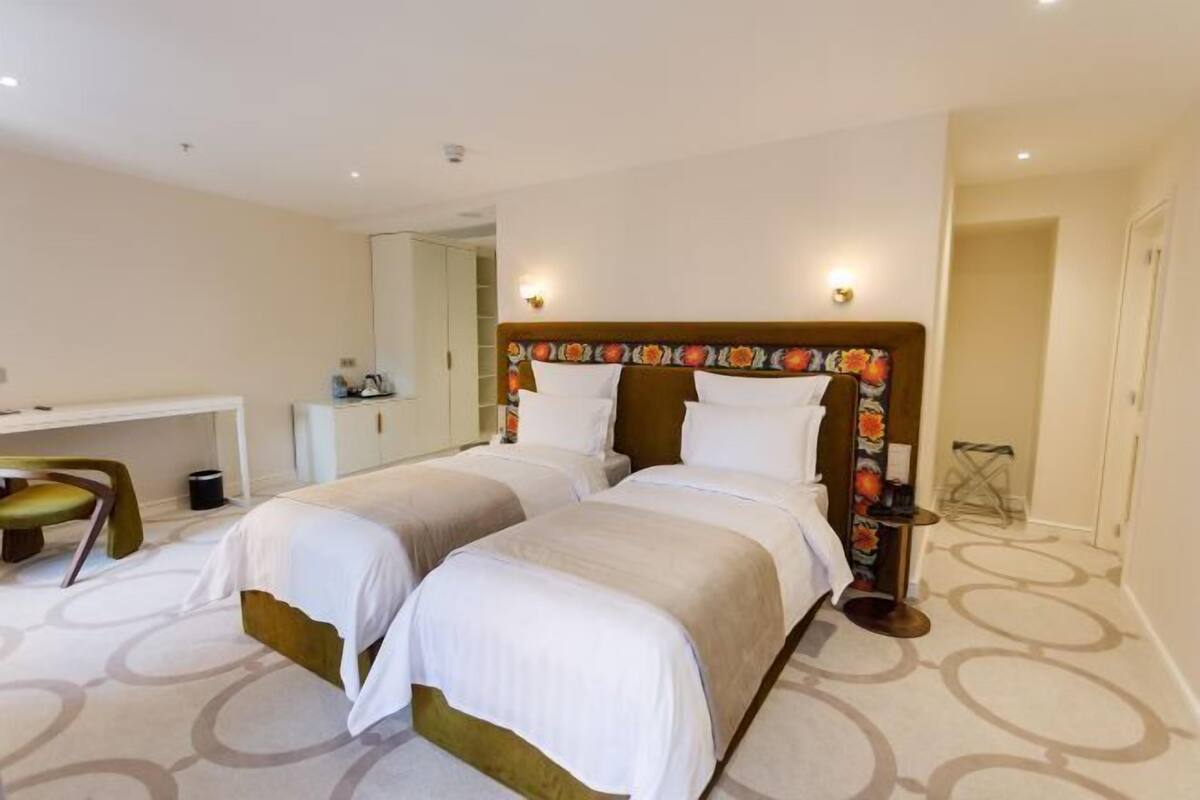 A hotel room with two beds, a desk, and a chair.