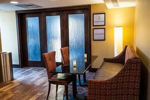 A hotel room with a dining table, two chairs, a sofa, and a large window with a view. - Hampton Inn Harrisburg-east (Harrisburg)