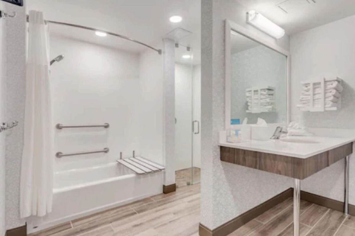 Un baño moderno con ducha, lavamanos y espejo.