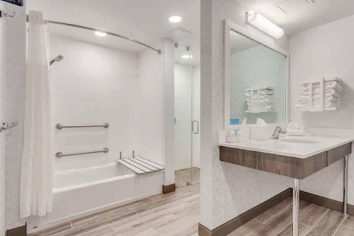 A modern bathroom with a shower, a sink, and a mirror.