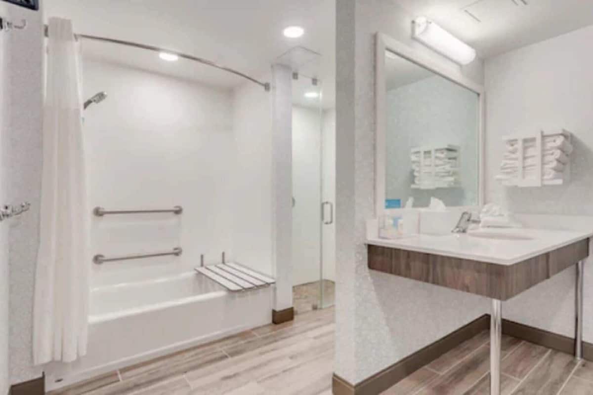 A modern bathroom with a shower, a sink, and a mirror.