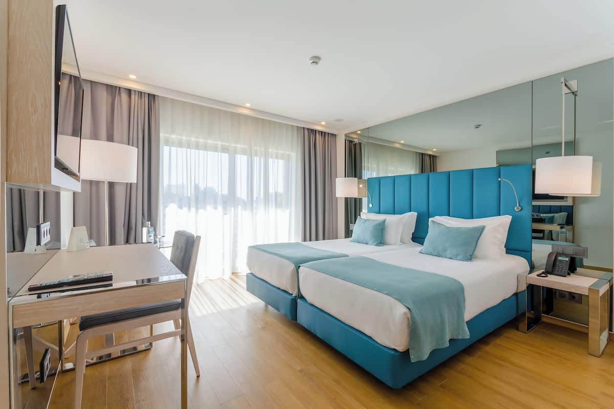Quarto de hotel moderno com uma cama grande, uma escrivaninha e uma cadeira.