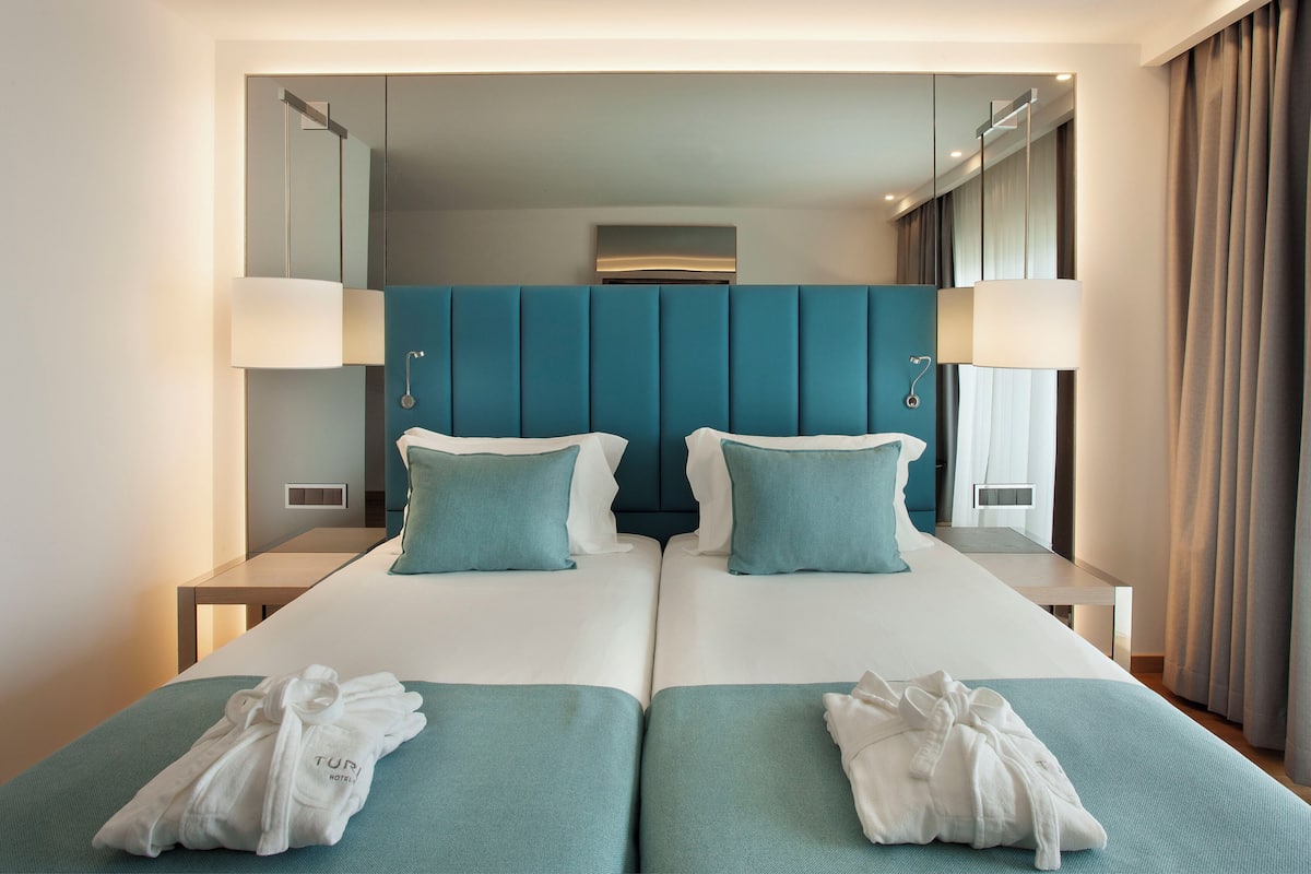 Quarto de hotel com uma cama grande, duas mesas de cabeceira, uma cabeceira e vista do interior do quarto.