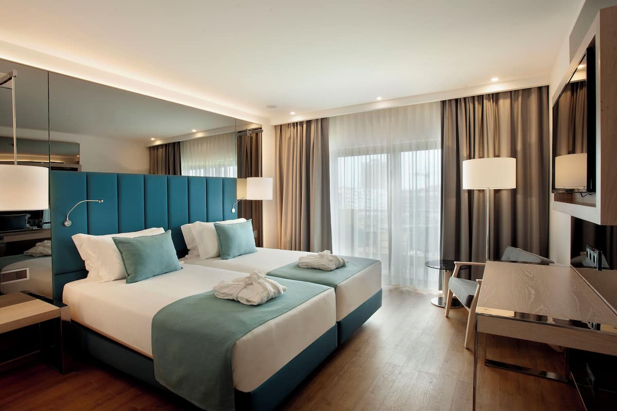 Quarto de hotel moderno com uma cama grande, uma escrivaninha e uma televisão.
