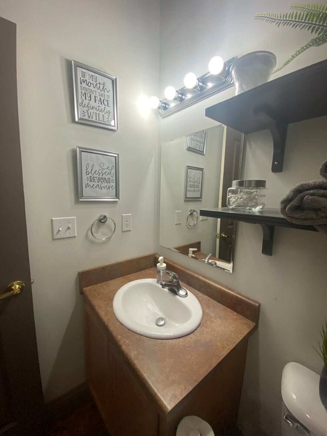 A bathroom with a sink, mirror, and lighted vanity.