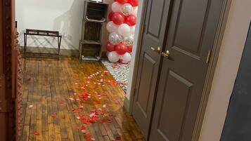 A hallway with wooden flooring, a door, and a wall decorated with red and white balloons.