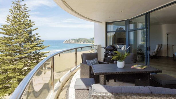 Ein Balkon mit Korbmöbeln, einem Tisch und einem Blumentopf.