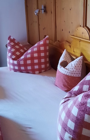 A bed with a checkered pillow and a polka-dotted pillow.