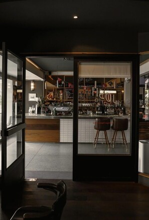 Una zona de bar con taburetes y mostrador, una ventana con vistas, y una puerta que da a otra habitación.