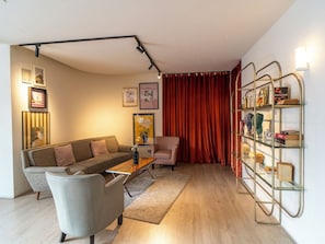 A modern living room with a sofa, armchair, coffee table, and a bookshelf. - Josh Hotel (Bangkok)